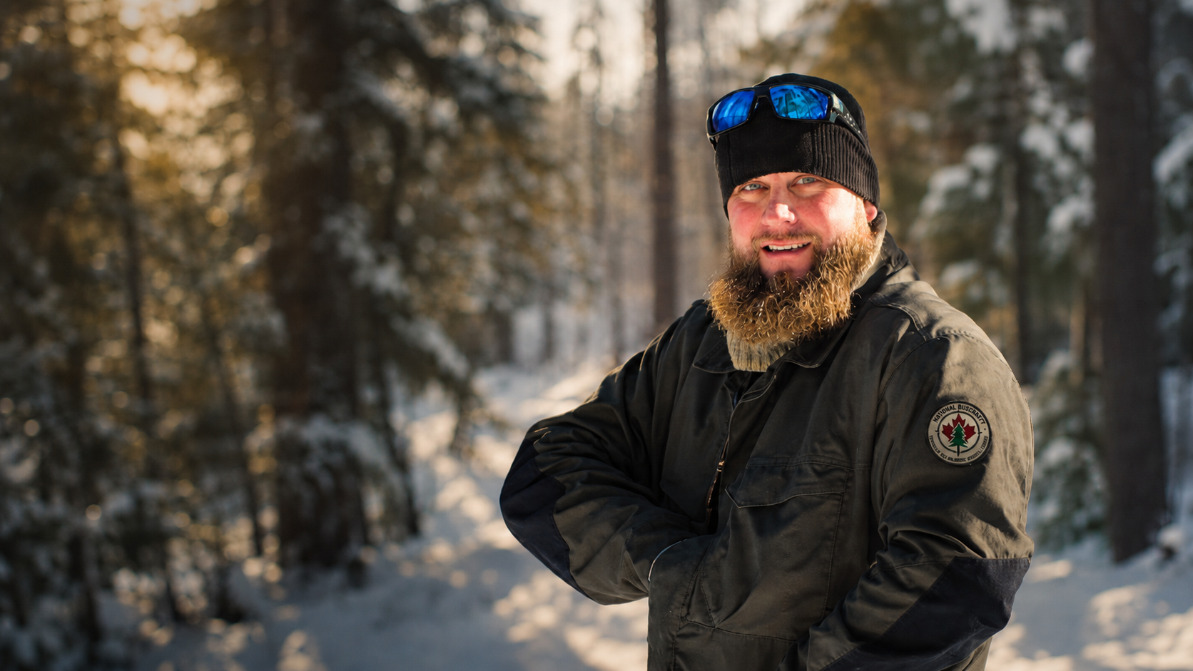 An NBWSR instructor in winter gear standing in a snowy boreal forest